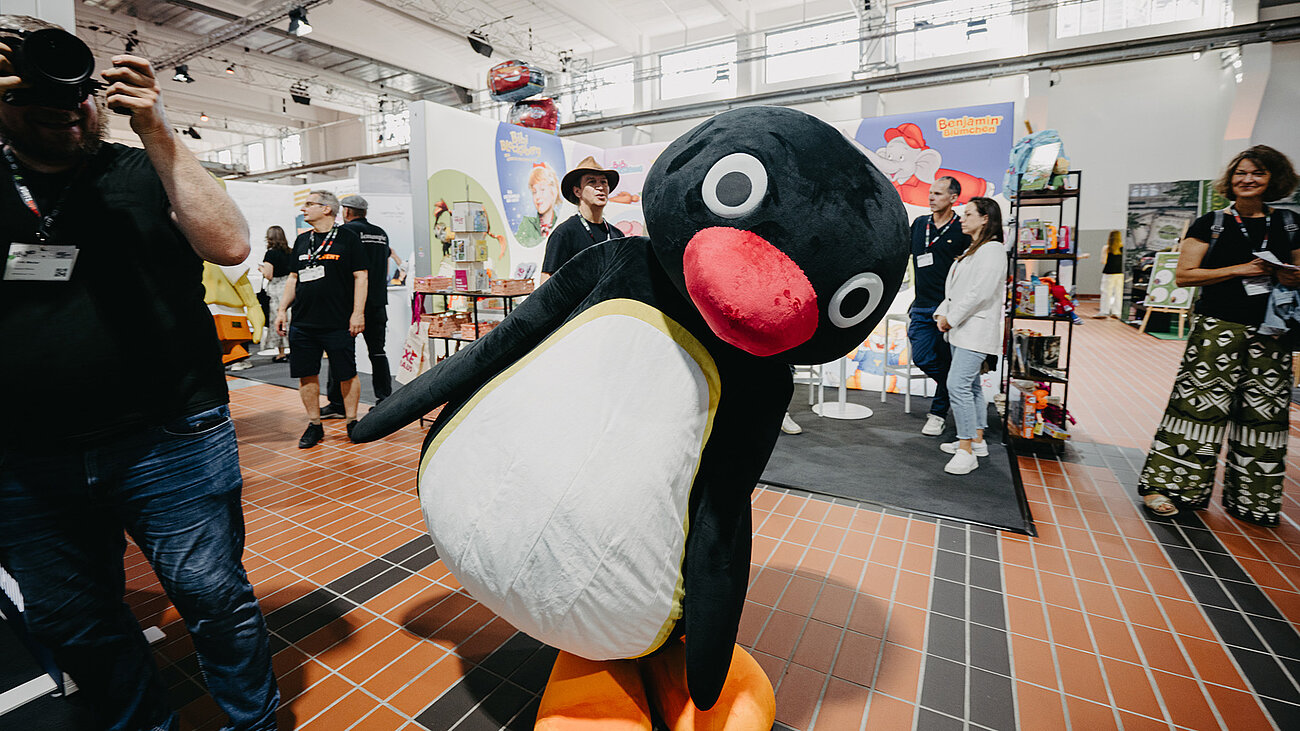 Pingu the mascot walks through the BRANDmania hall.