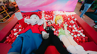 Two mascots and a woman in the ball pit.