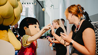 Mascot "Heidi" shakes hands with woman.